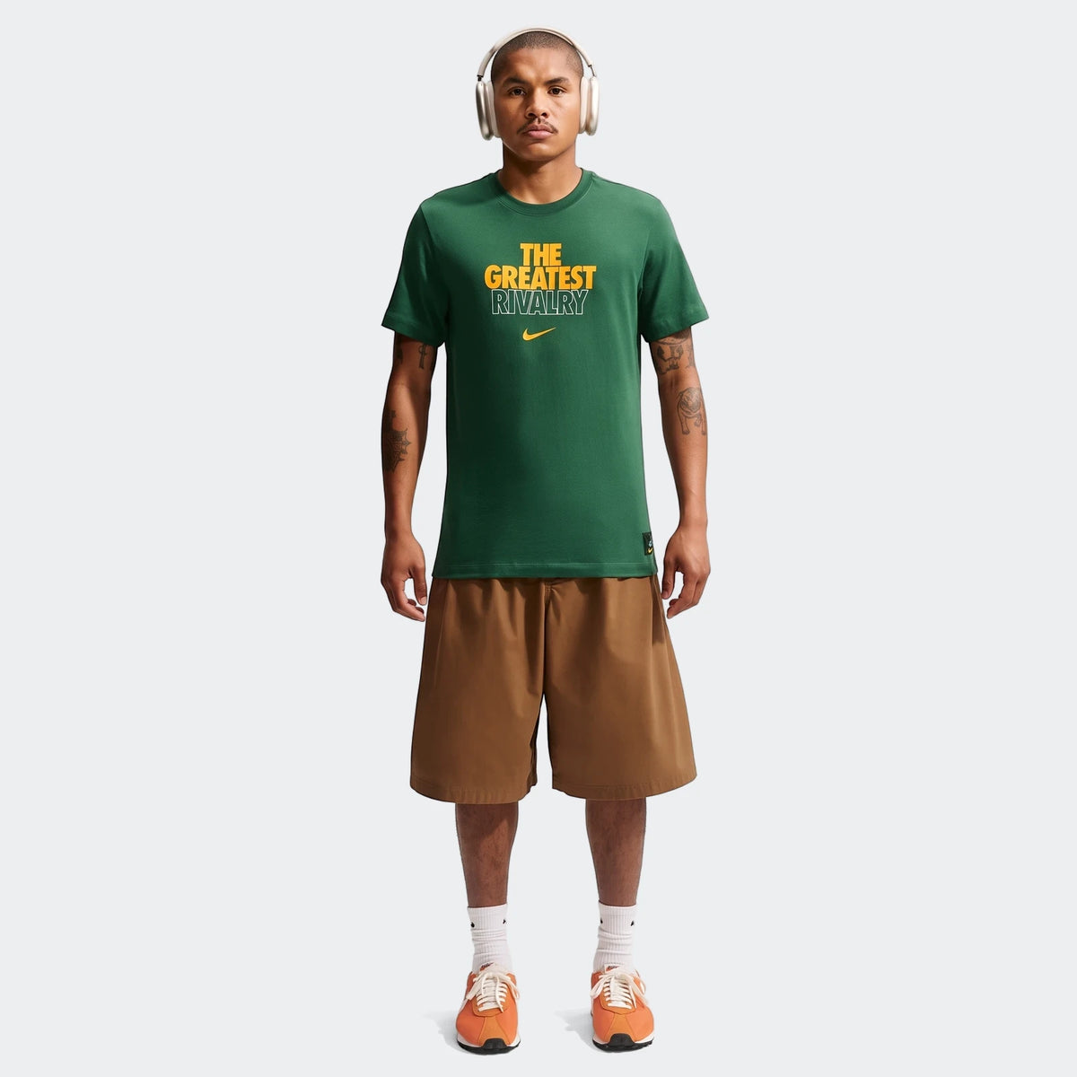 Male model wearing a dark green 2026 Nike Springboks Rugby's Greatest Rivalry Tour Men T-shirt, brown shorts, and orange