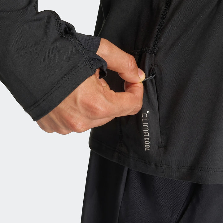 Close-up of a person wearing a black Adi365 Full-Zip Sweatshirt, with a hand pulling the side zipper. Features a Climacool