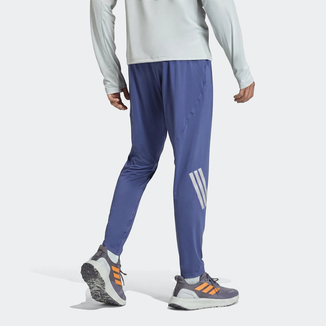 Adi365 Track Pants in blue with reflective stripes, worn by a male model with dark grey and orange running shoes.