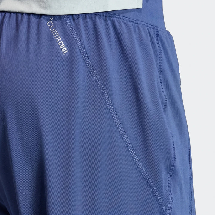 Close-up of Adi365 Track Pants in blue performance fabric with CLIMACOOL logo and visible stitching details.