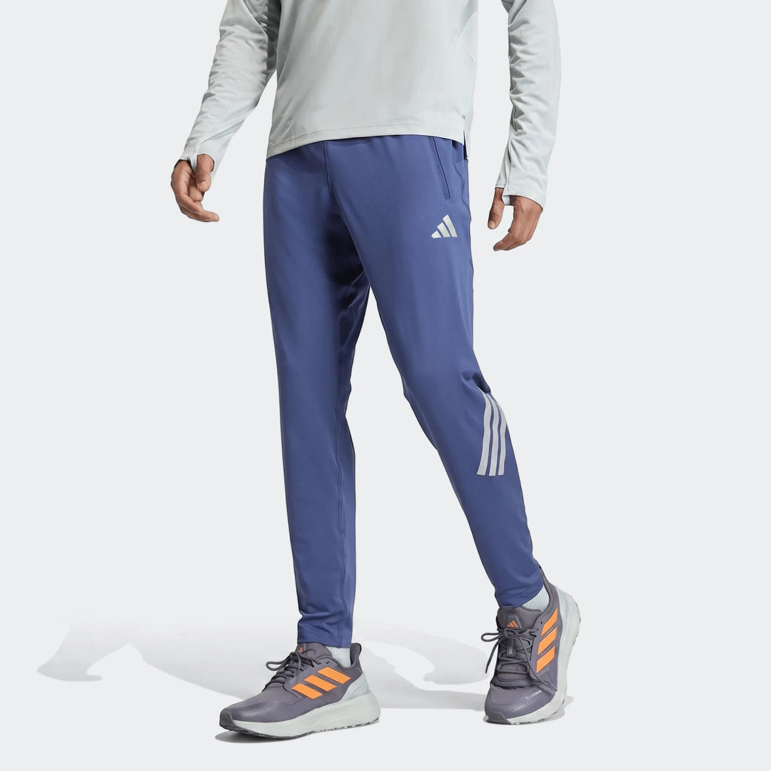 Adi365 Track Pants in blue with tapered legs, zip side pockets, and three-stripe detail on the calf.