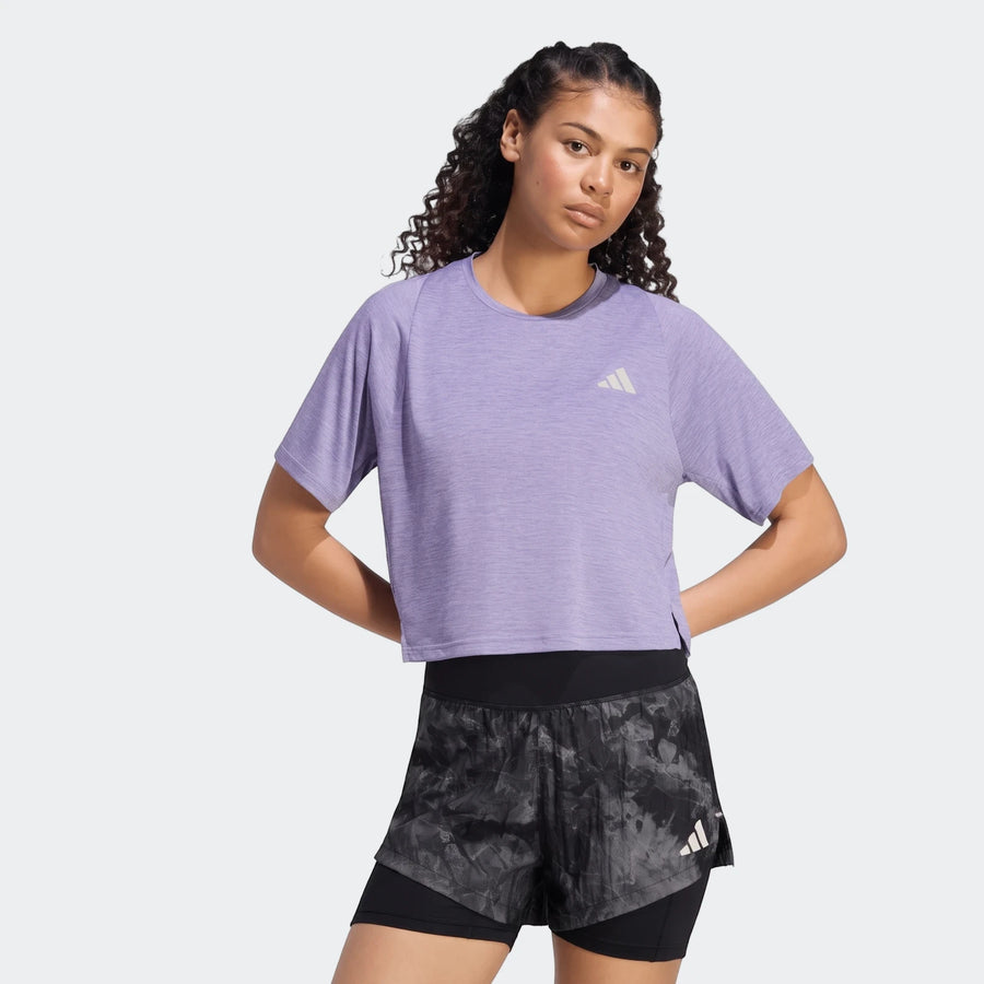 Woman wearing a purple Adidas Adi365 Soft Touch T-Shirt with short sleeves and black patterned running shorts, posing