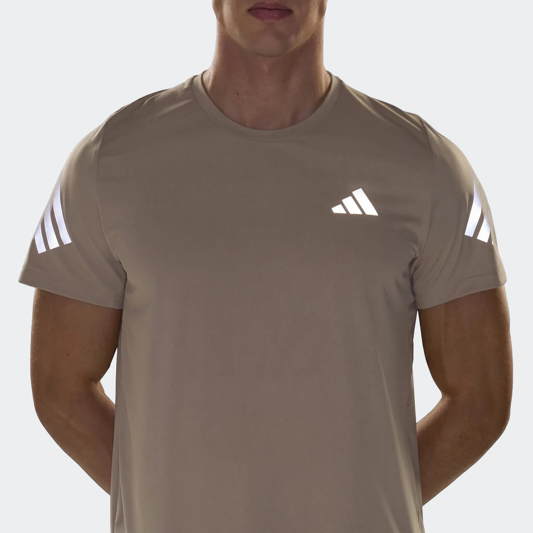 Light brown Adidas Adi365 T-Shirt for men, featuring a reflective logo and stripes on the sleeves, shown in a close-up.
