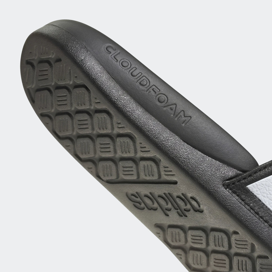 Close-up of black Adidas Adilette Comfort 2.0 slides sole, showing CLOUDFOAM and adidas branding, with textured outsole.
