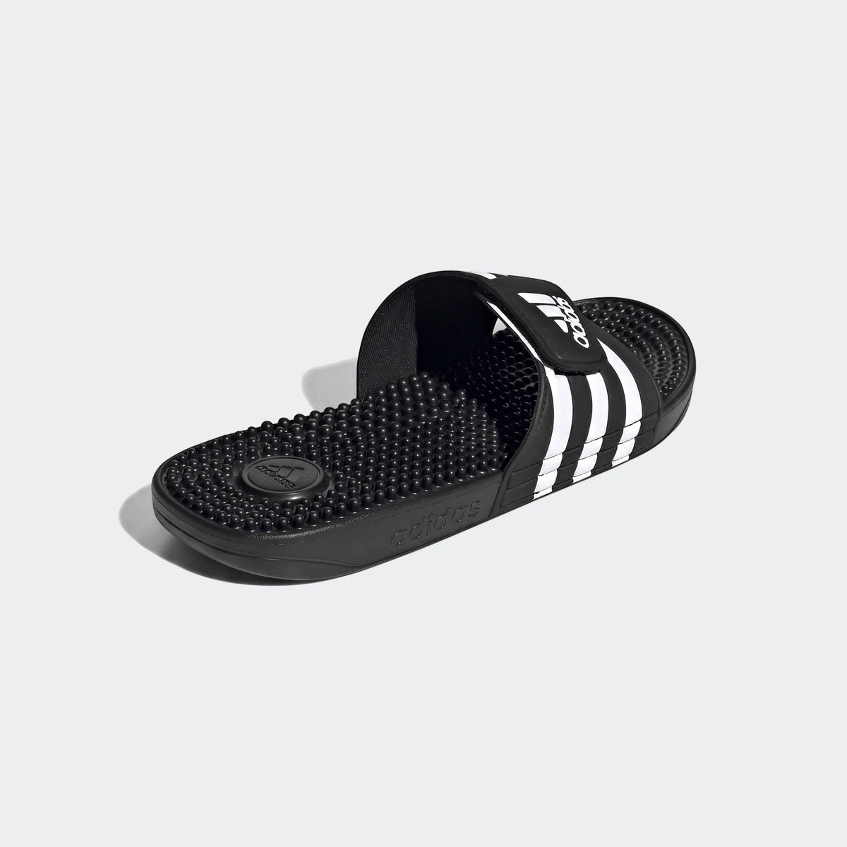 Black and white Adidas Adissage slides with massage nubs, viewed from an angled perspective.