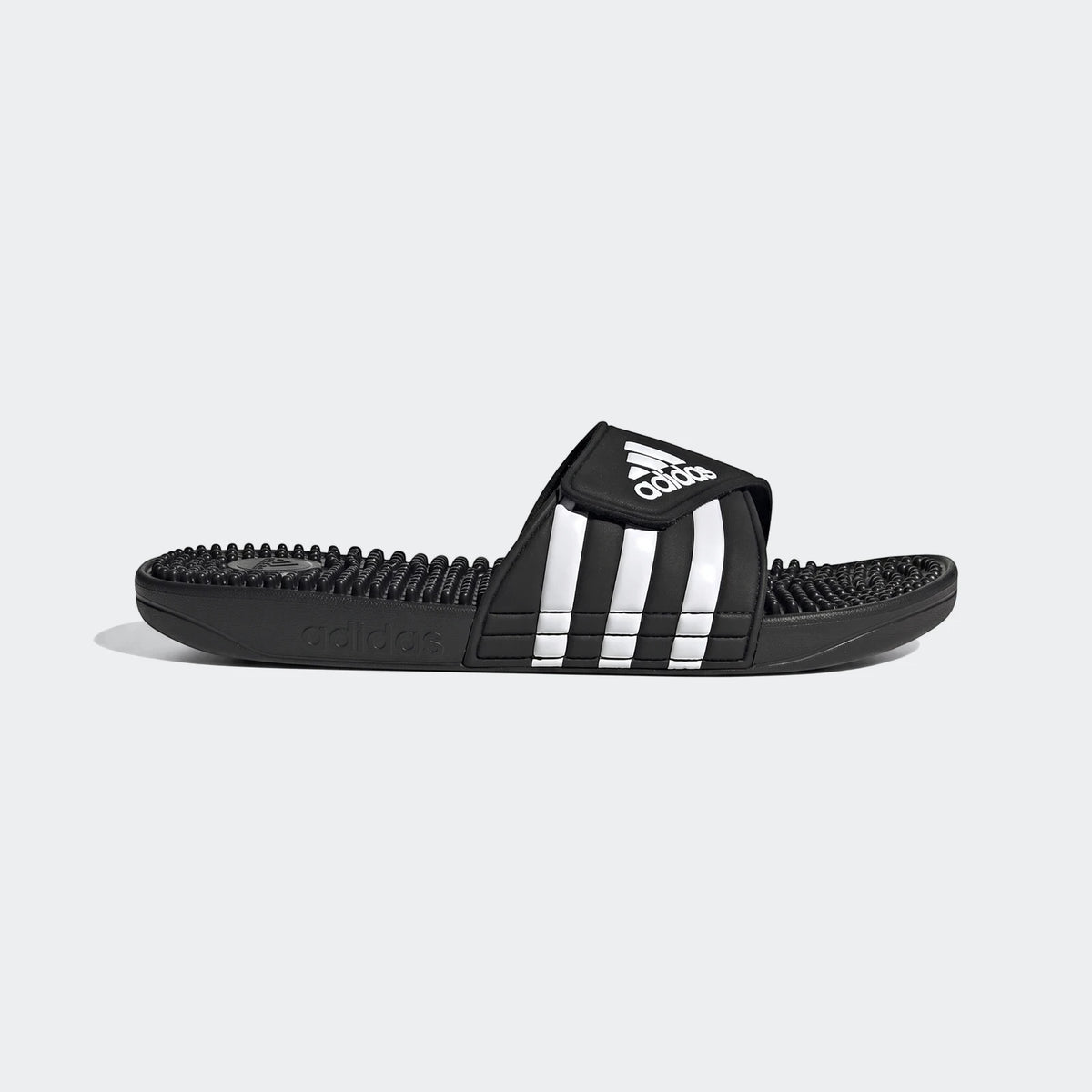 Black Adidas Adissage slides with white three-stripes on the strap and a textured footbed, shown in a side profile view.
