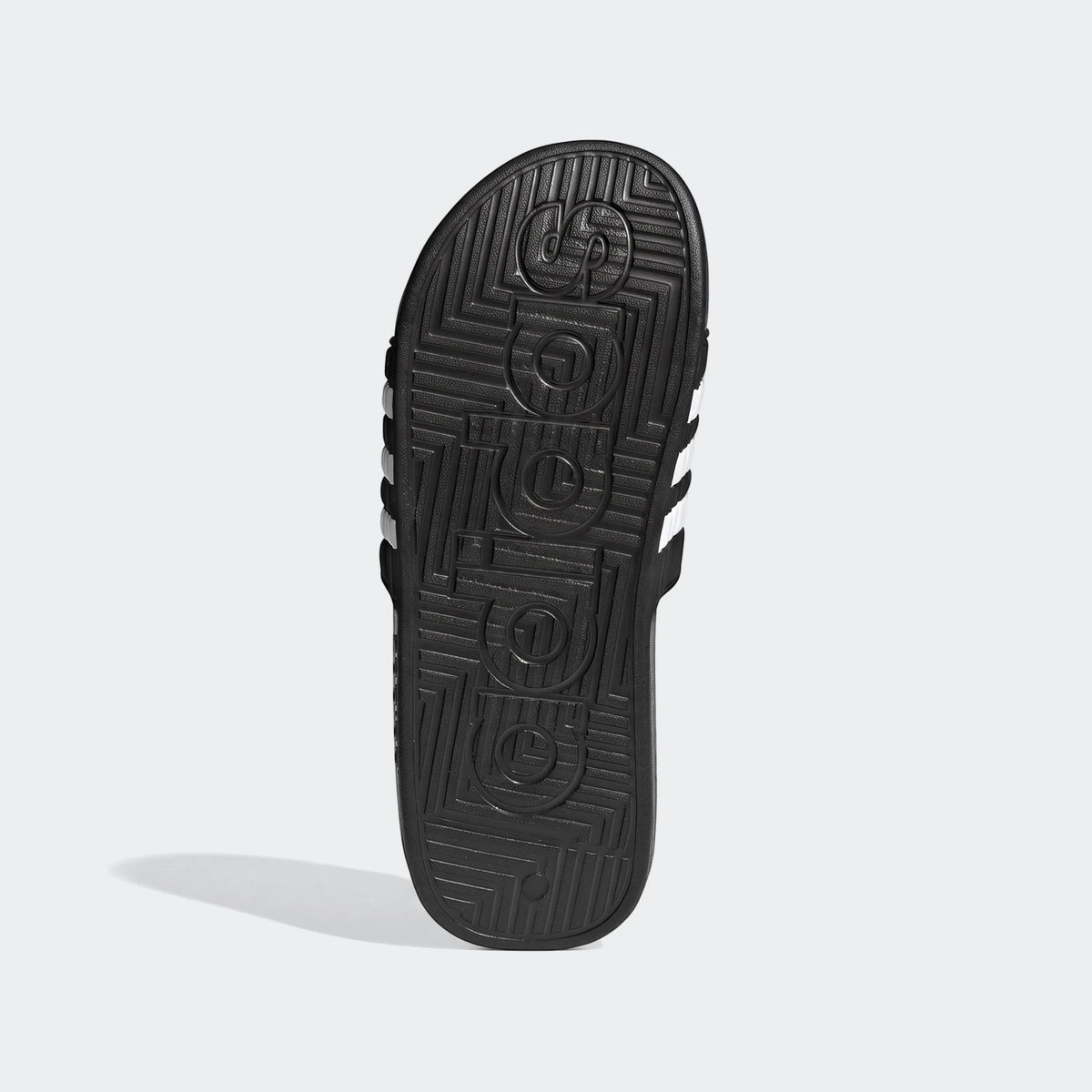 Black Adidas Adissage slides with white stripes, showing the textured sole with embossed branding on a white background.