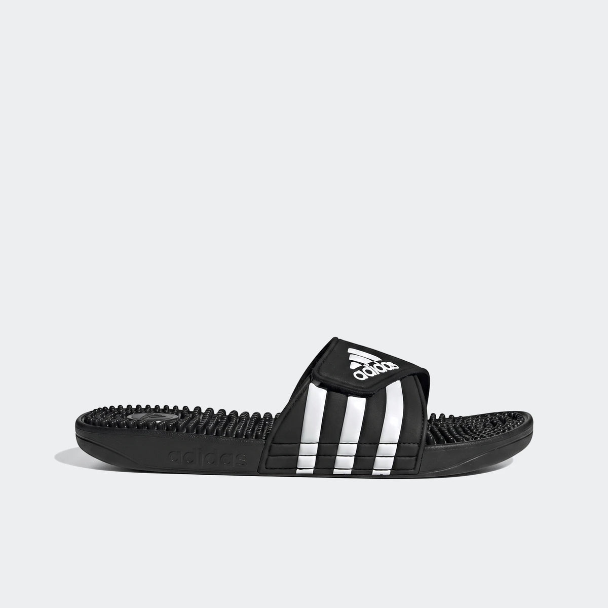 Black Adidas Adissage slides with three white stripes and a textured massage footbed, shown in a side view.