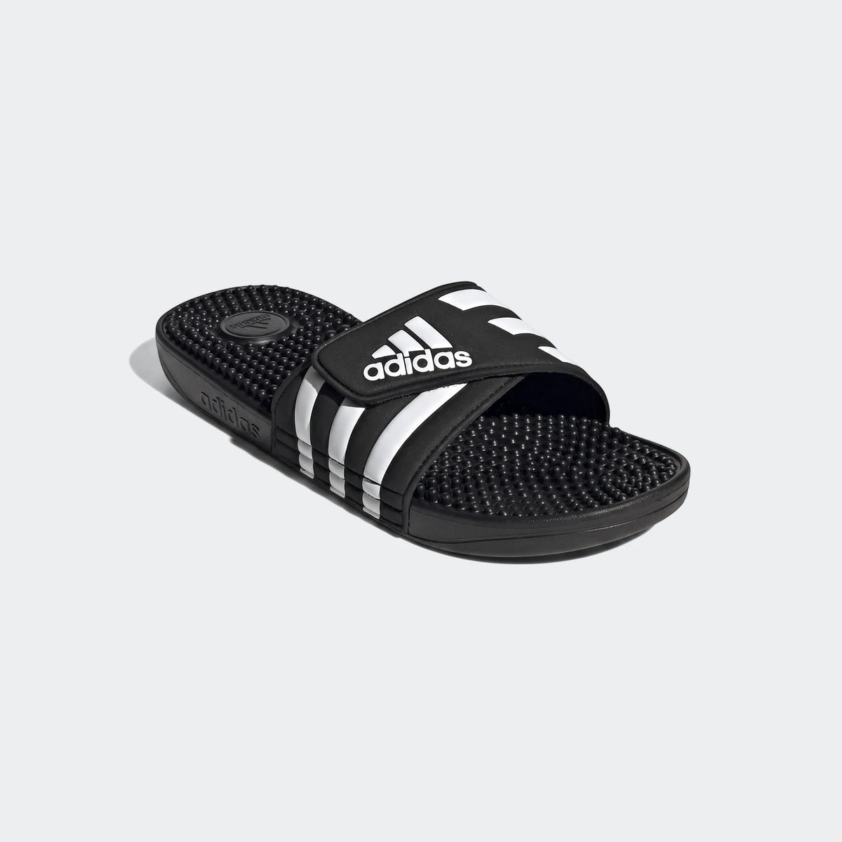 Black Adidas Adissage Slides with white stripes and a textured footbed, presented in an angled studio shot.