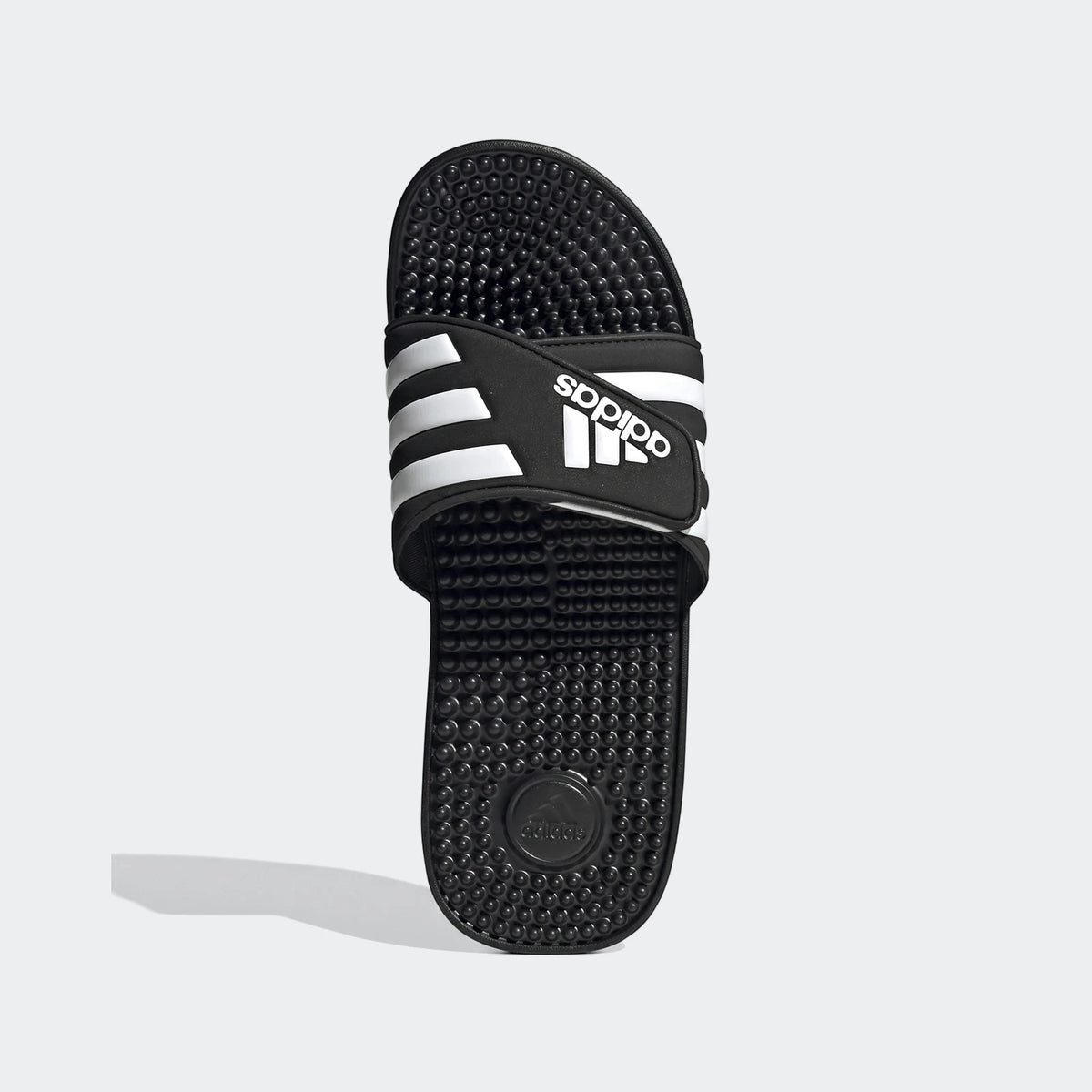 Black and white Adidas Adissage slides, top-down view. Features a black footbed with textured nubs and a white-striped