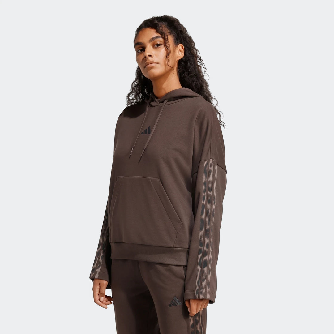 Woman wearing a brown Adidas All-Over Print Infill French Terry Hoodie with leopard print stripes and matching sweatpants.