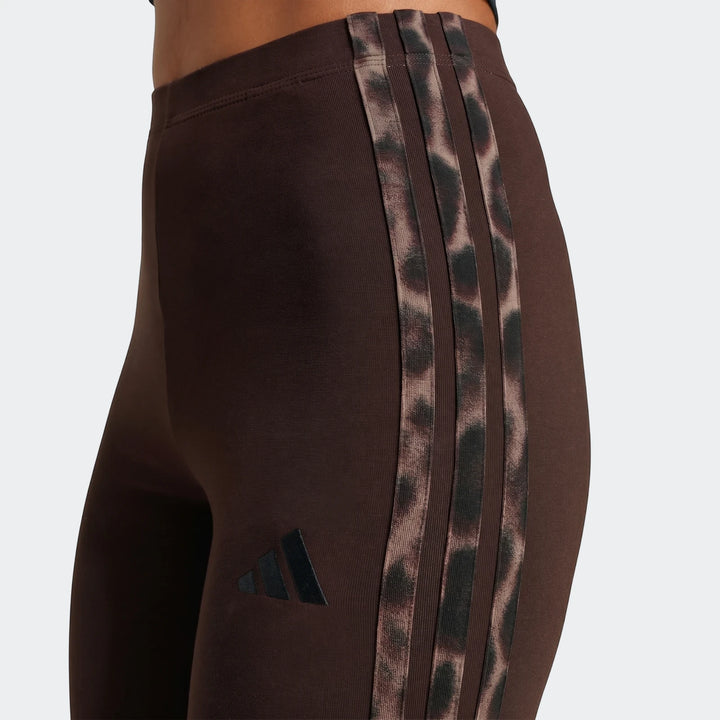 Close-up of brown Adidas All-Over Print Infill Leggings with leopard print three stripes worn on a model.