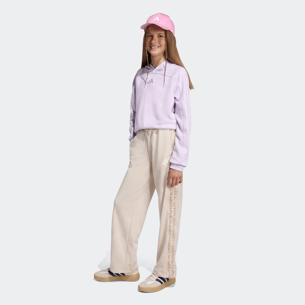 Young girl wearing Adidas Angled 3-Stripes French Terry Pants in beige, a purple hoodie, pink cap, and sneakers, full body