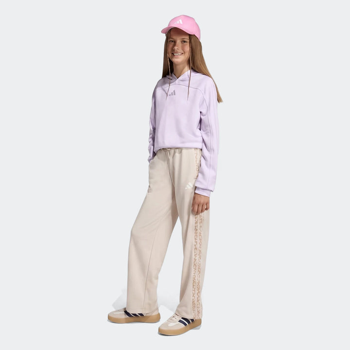 Young girl wearing Adidas Angled 3-Stripes French Terry Pants in beige, a purple hoodie, pink cap, and sneakers, full body