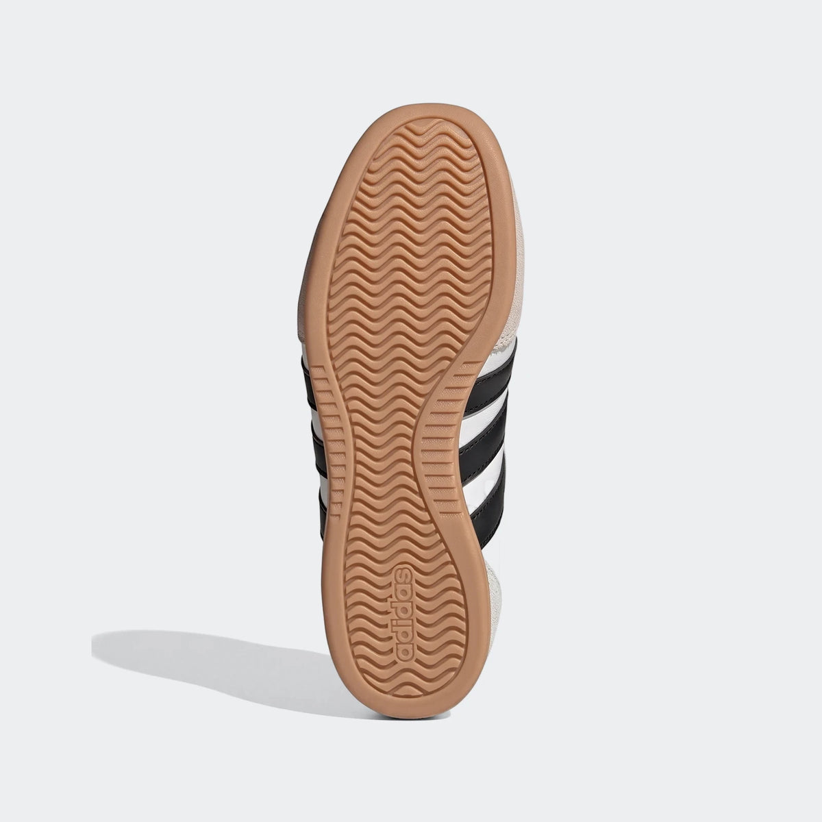 Sole of a white Adidas Barreda Mary Jane shoe with black stripes and a brown wavy rubber outsole featuring the Adidas logo.