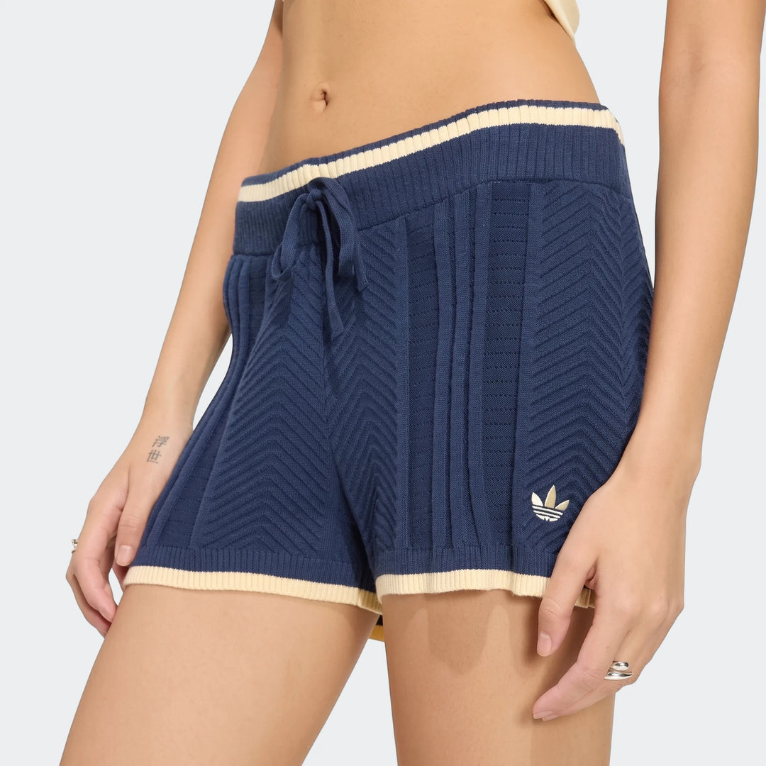 Close-up of a person wearing navy blue Adidas Cable Knit Shorts with cream stripes and a drawstring waist, showcasing the