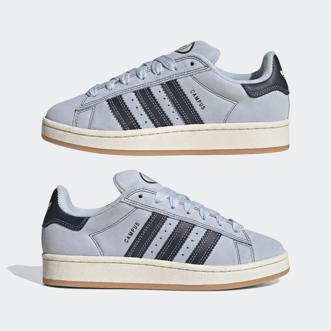 Two light blue Adidas Campus 00S suede sneakers with dark blue stripes and white midsoles, displayed on a plain background.
