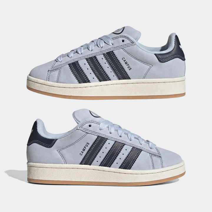 Two light blue Adidas Campus 00S suede sneakers with dark blue stripes and white midsoles, displayed on a plain background.