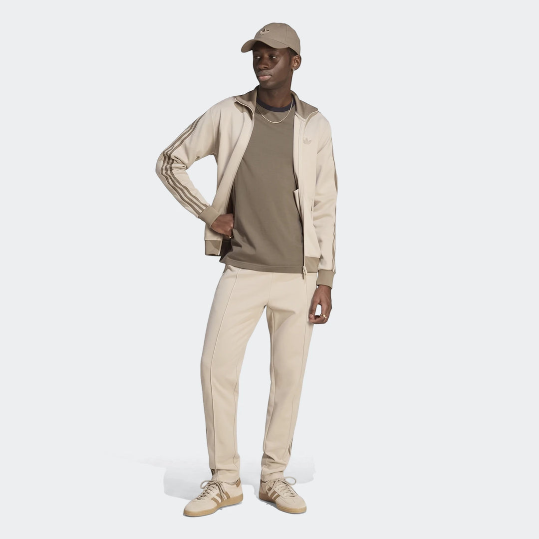 Man wearing a beige Adidas Classic Track Top and matching track pants, cap, and sneakers, shown full body.