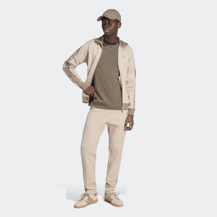 Man wearing a beige Adidas Classic Track Top and matching track pants, cap, and sneakers, shown full body.