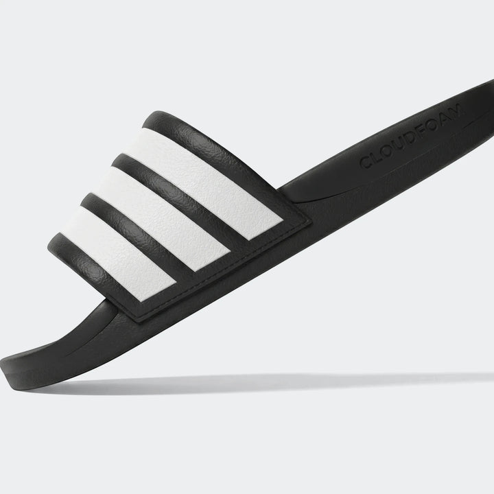 Black and white Adidas Cloudfoam slide sandal with three signature stripes, shown at an angle.