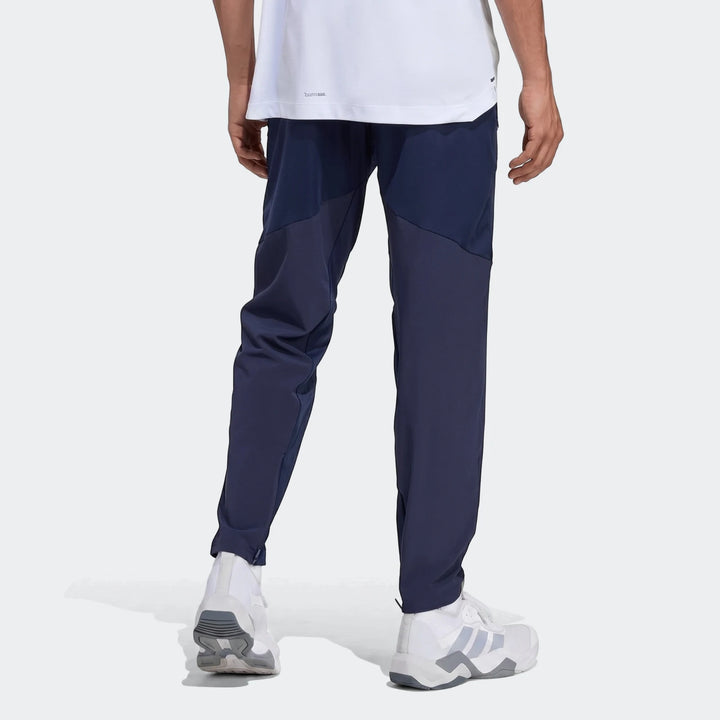 Navy blue Adidas D4T Hybrid Pants for men, worn by a model from the back. These athletic pants feature darker blue panels