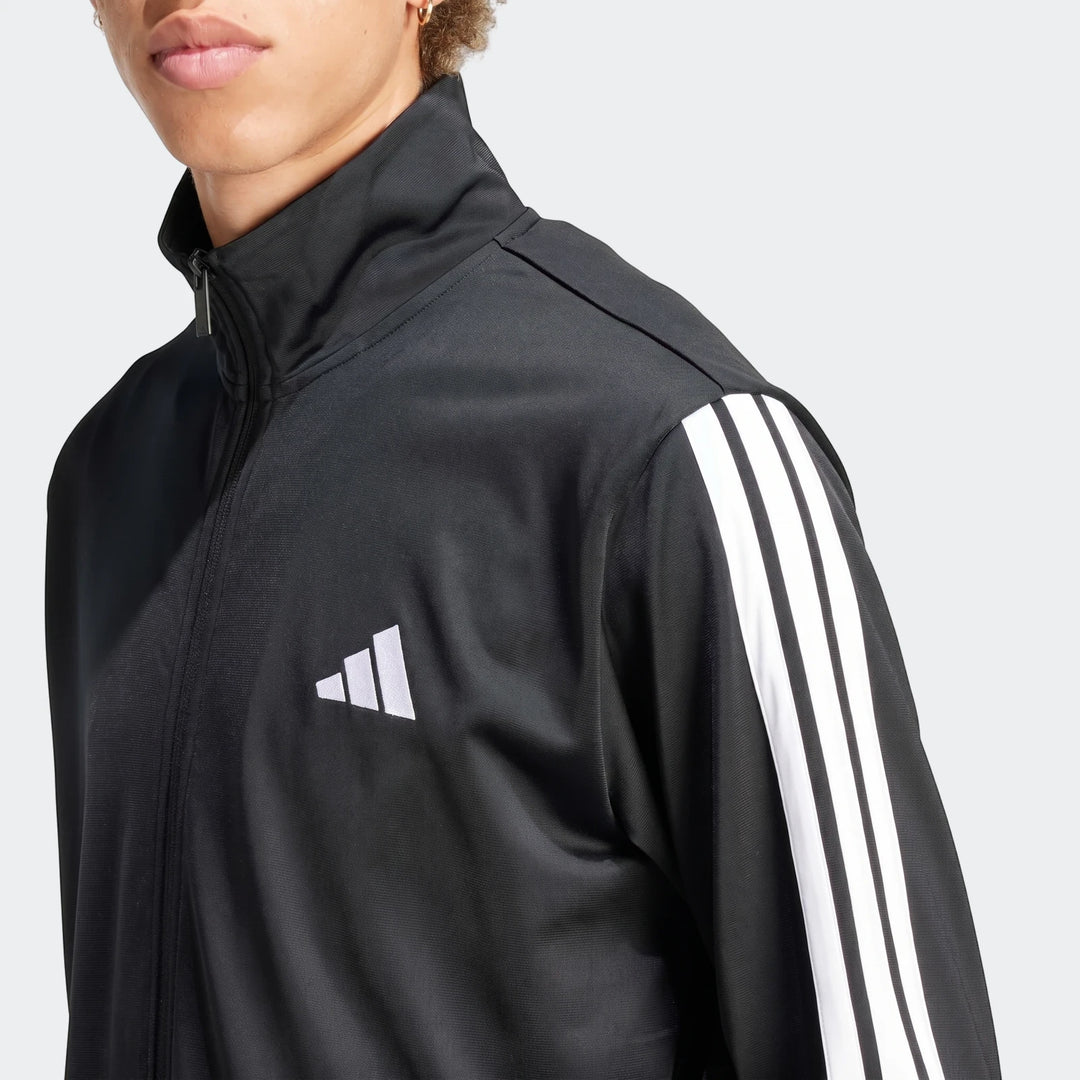 Close-up of a person wearing a black Adidas Dayready Tracksuit jacket with white stripes on the sleeve and the Adidas logo