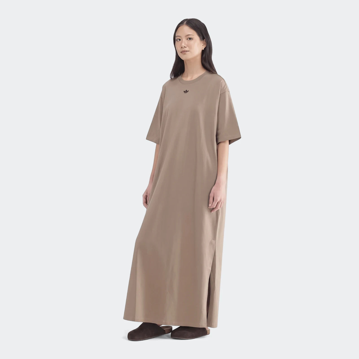 Full-body view of a model wearing an Adidas Essential beige long t-shirt dress with short sleeves and dark brown slip-on