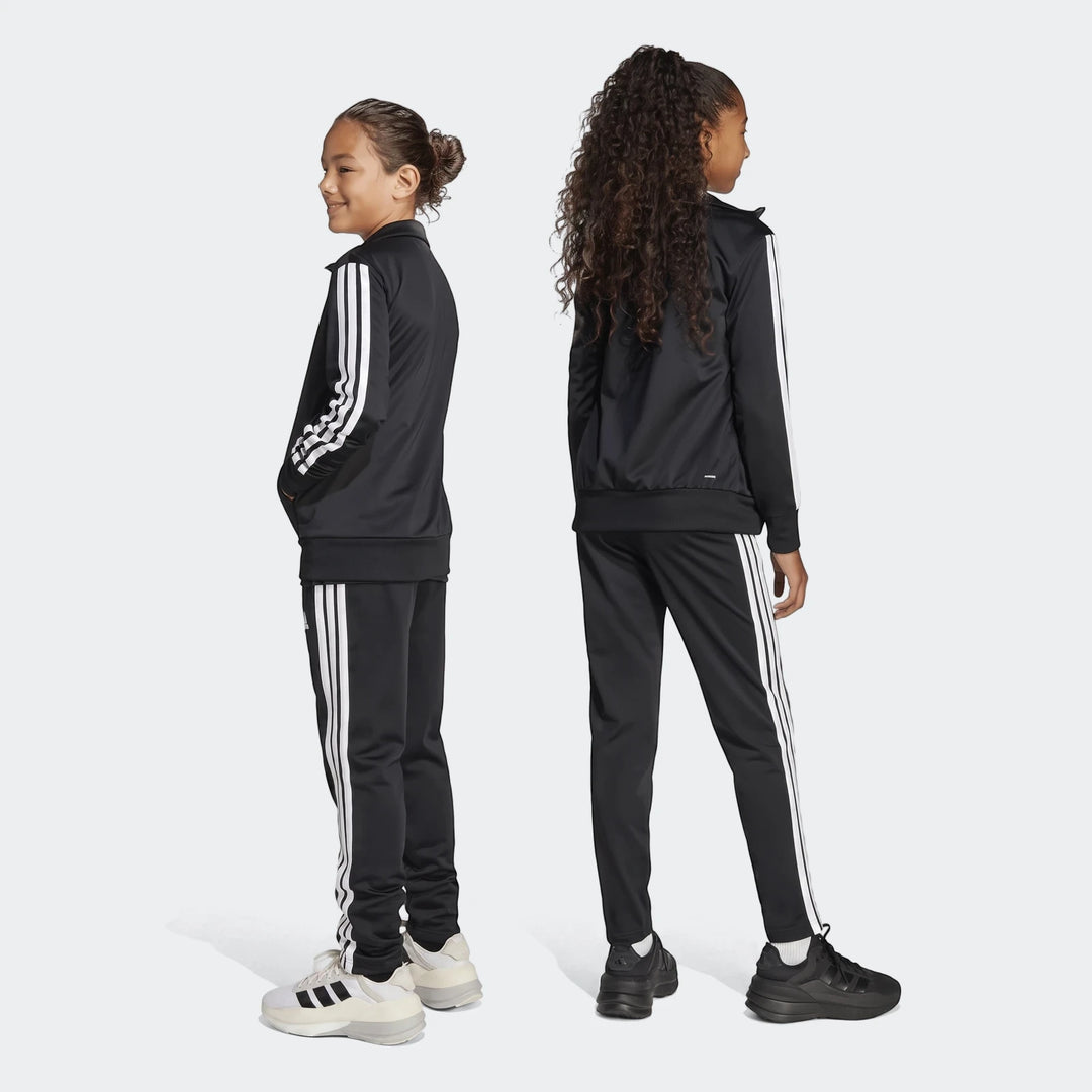 Two girls in black Adidas Essentials Climacool Track Suits with white stripes, standing in a side view.