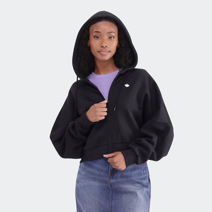 Black Adidas Essentials Full-Zip Hoodie worn by a woman with curly hair, paired with a blue denim skirt. Front view.