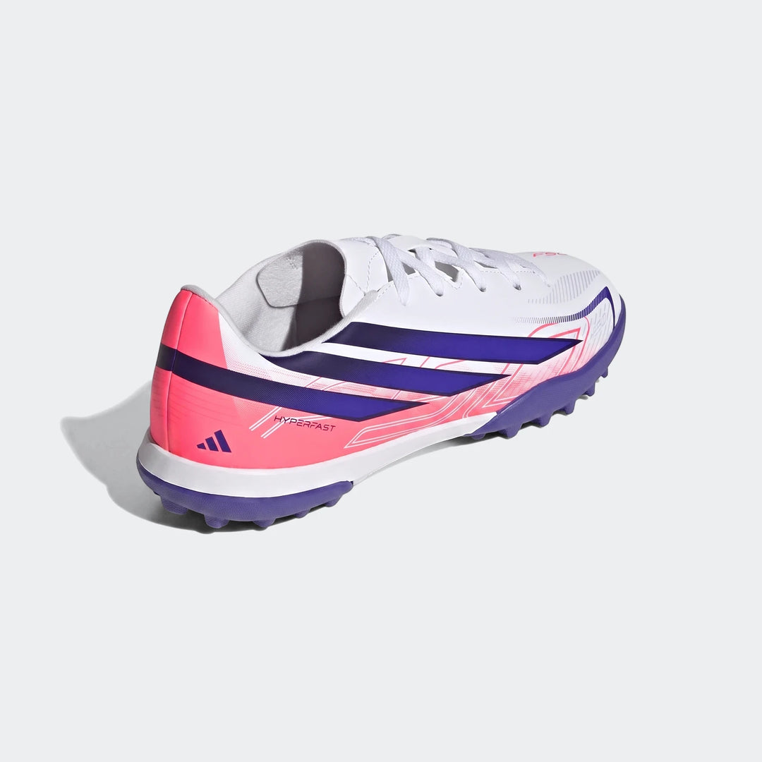 Kids Adidas F50 Hyperfast Club Turf football boots in white, vibrant pink, and deep purple, featuring studded soles for turf