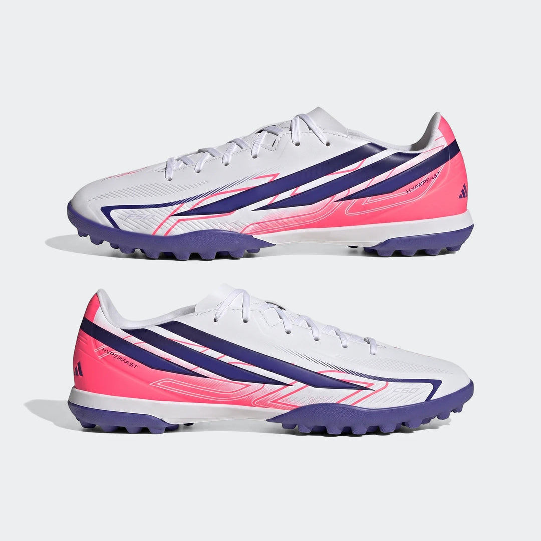 Two white, blue, and pink Adidas F50 Hyperfast Club Turf Football Shoes are displayed from a side view, highlighting the