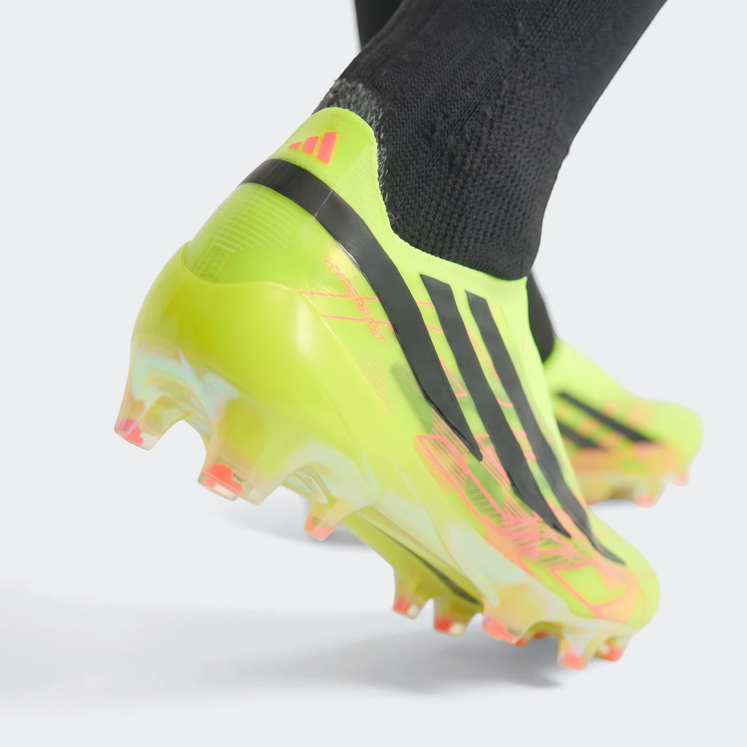 Close-up of a fluorescent yellow and black Adidas F50 Hyperfast Elite laceless firm ground boot with pink accents and