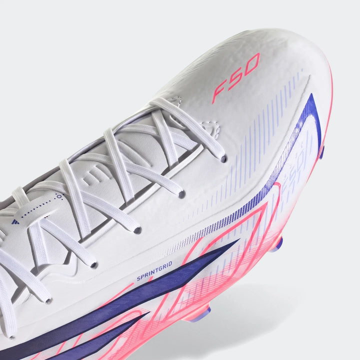 Close-up of a white Adidas F50 Hyperfast League Firm Ground Football Boot with pink F50 branding and blue graphic details.