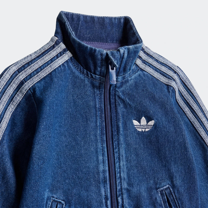 Blue denim Adidas Firebird Track Top, with white three stripes on shoulders and an embroidered trefoil logo, full-zip front.