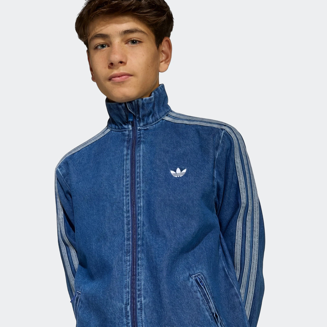 Close-up shot of a young man wearing a blue Adidas Firebird Denim Track Top with a stand-up collar and white stripes.