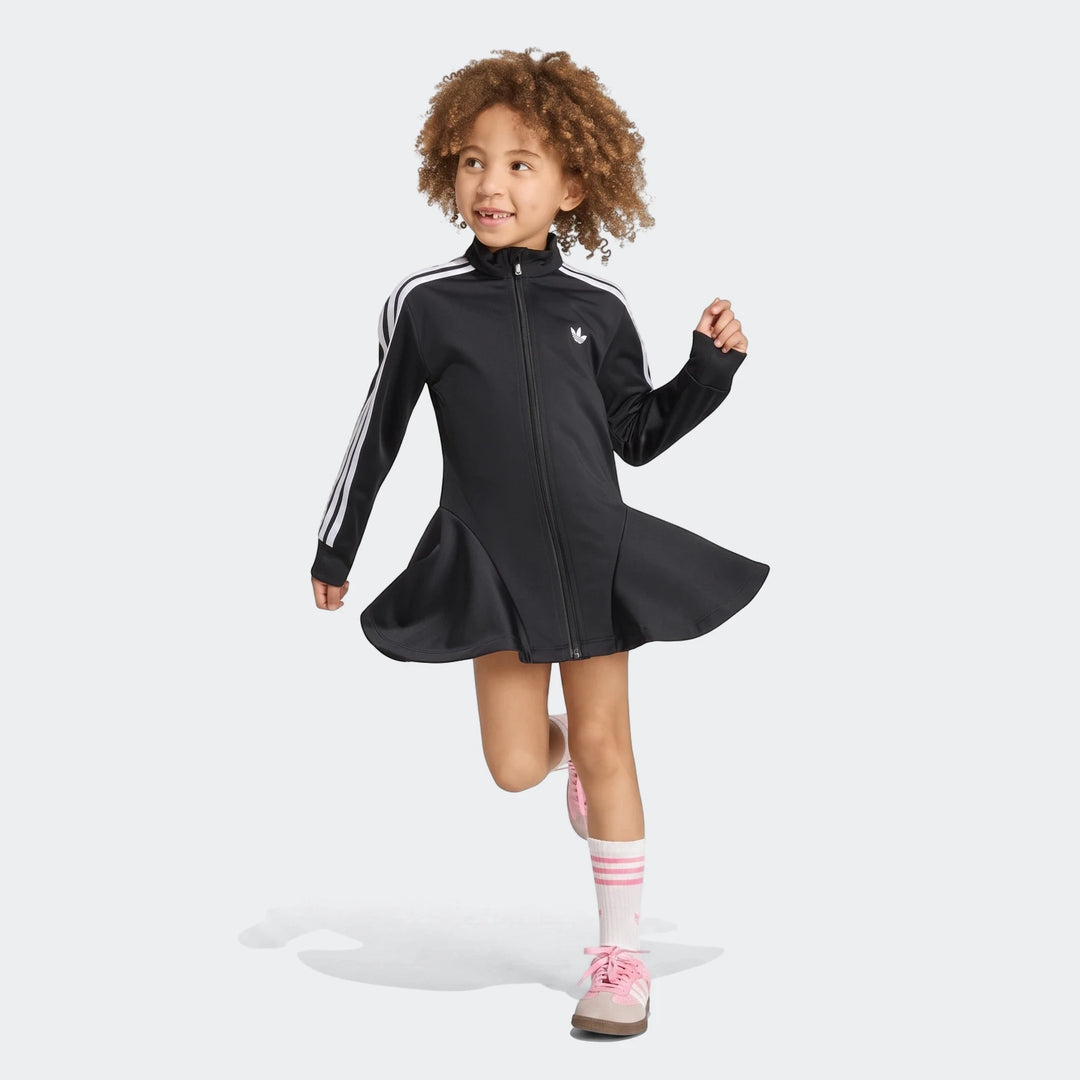 A young girl wears a black Adidas Firebird long sleeve dress with white stripes and a flared skirt.