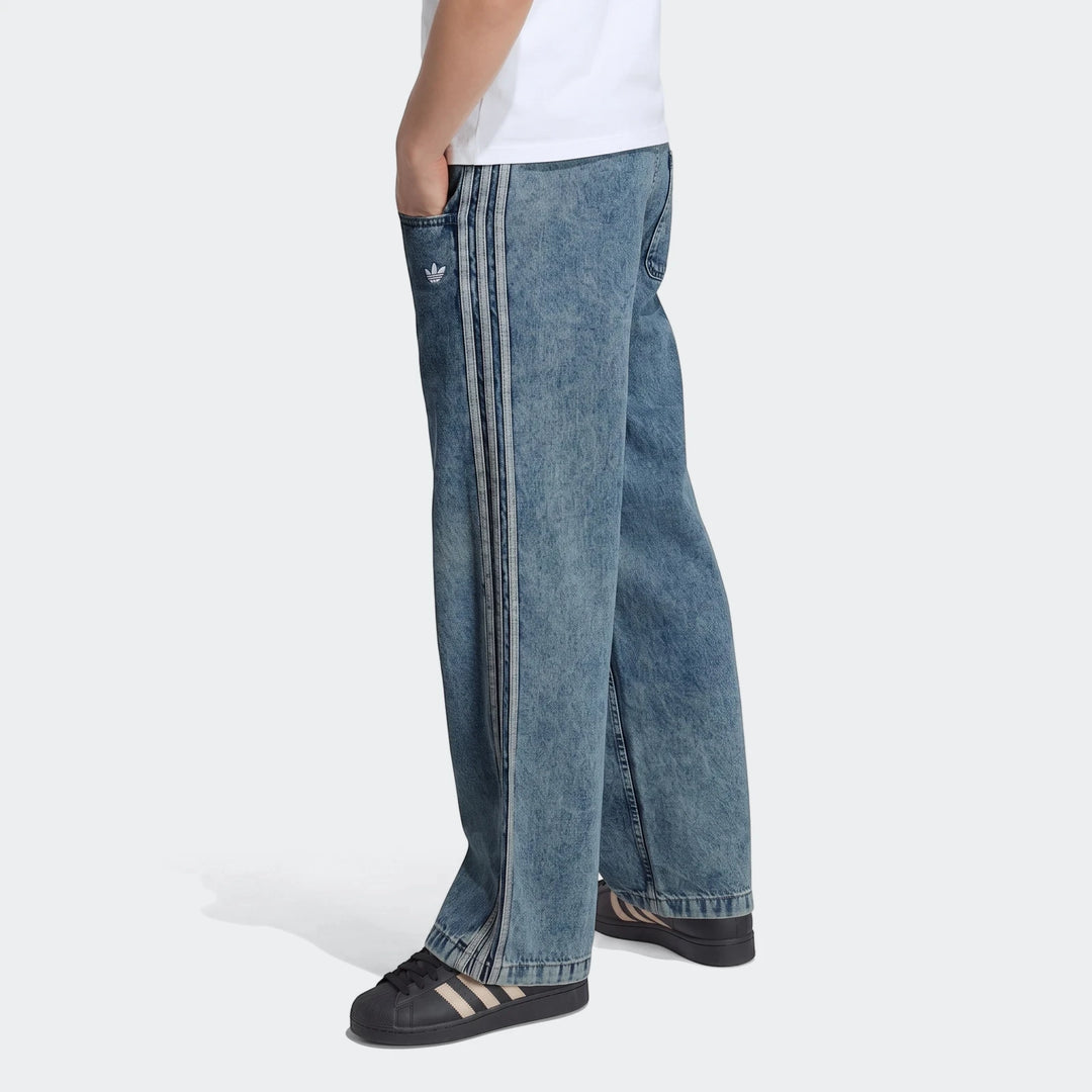 Blue acid wash Adidas Firebird loose denim track pants, featuring three stripes and an Adidas Trefoil logo on the pocket,
