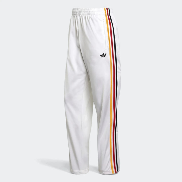 White Adidas Firebird Track Pants with iconic red, yellow, and black three-stripe design and Trefoil logo, shown from a side