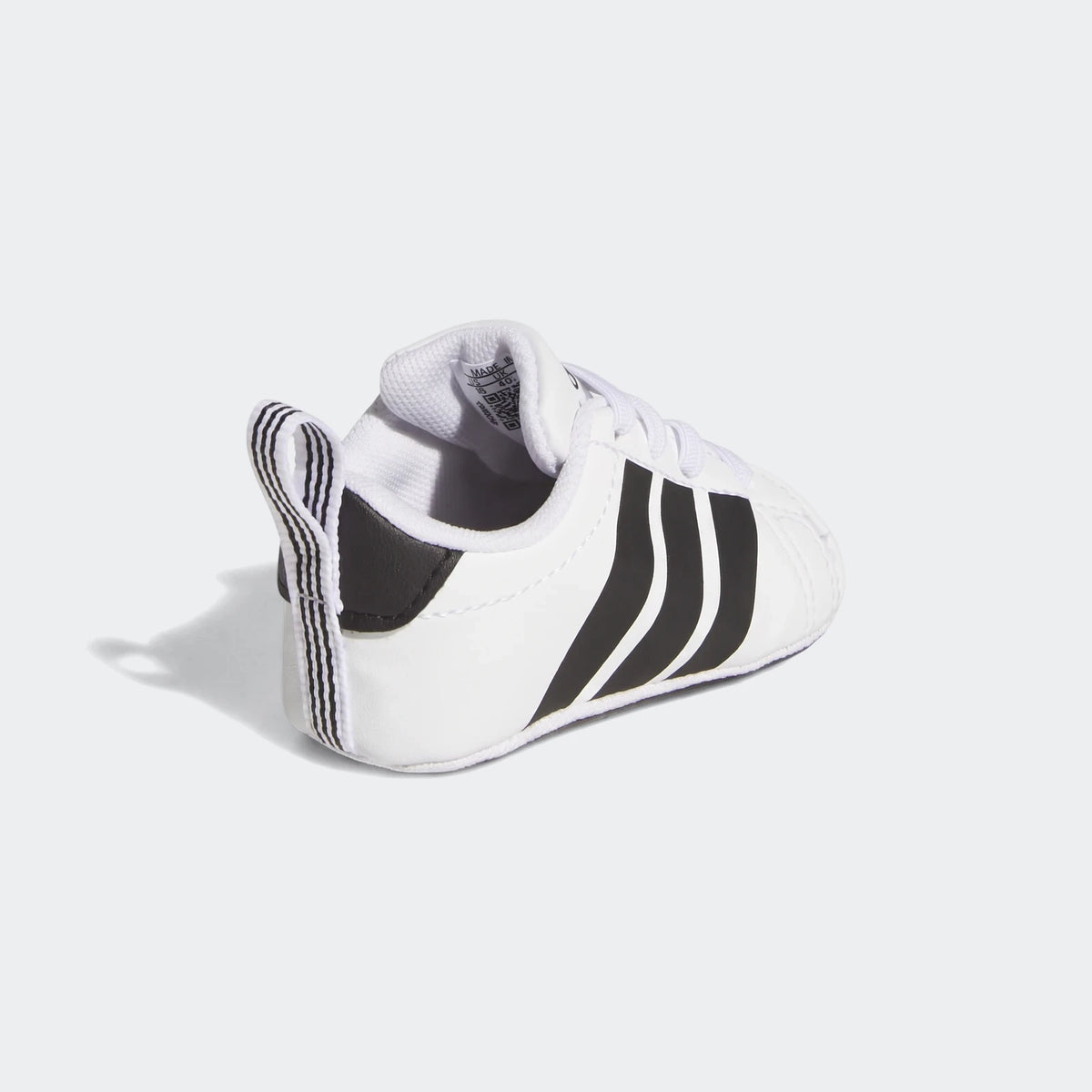 White Adidas Grand Court Crib baby shoe with black stripes, visible from the side and heel on a white background.