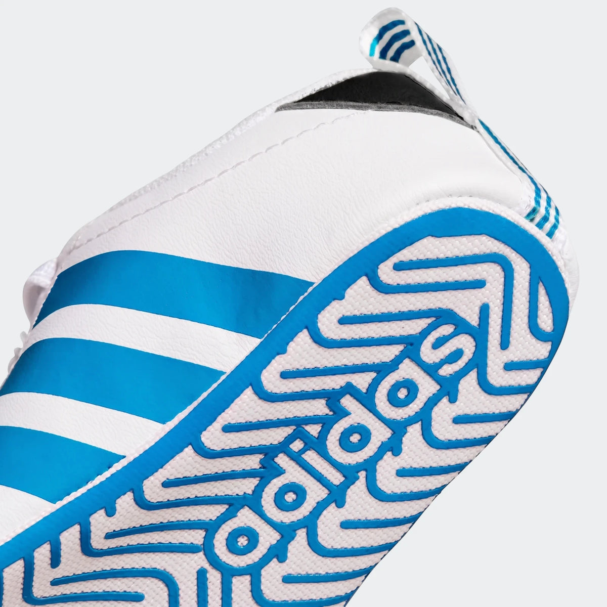 Close-up view of the white and blue Adidas Grand Court Crib shoe, showcasing the sole with the Adidas logo and blue stripes