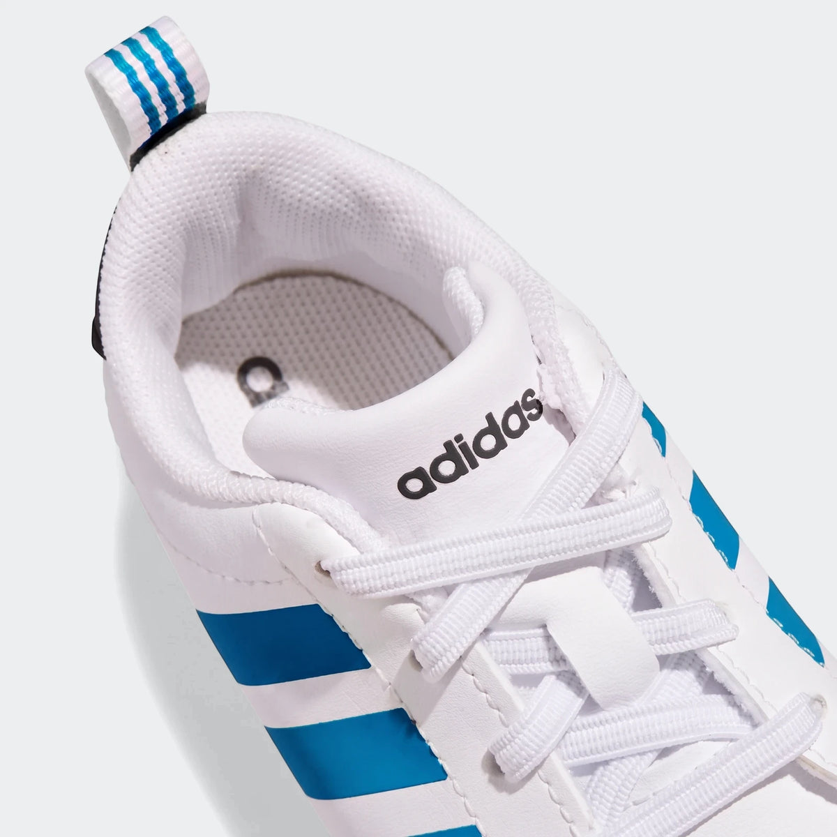 Close-up of a white Adidas Grand Court Crib shoe with blue stripes and white laces, designed for infants.