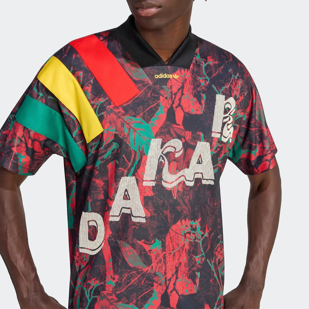 Close-up of a model wearing an Adidas Graphic Football Jersey with a vibrant red, green, and yellow abstract pattern and