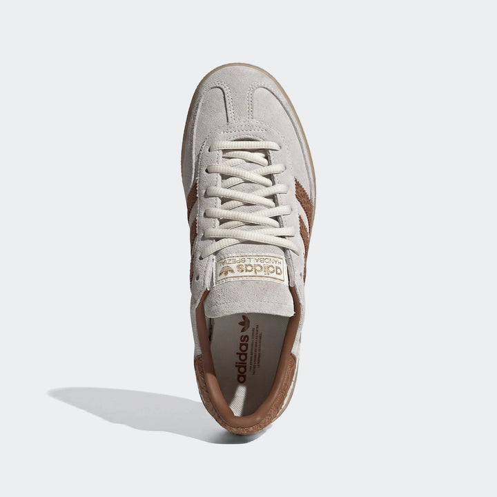 Creamy white Adidas Handball Spezial shoes with brown stripes and gum sole, top-down view. Classic low-profile sneaker.