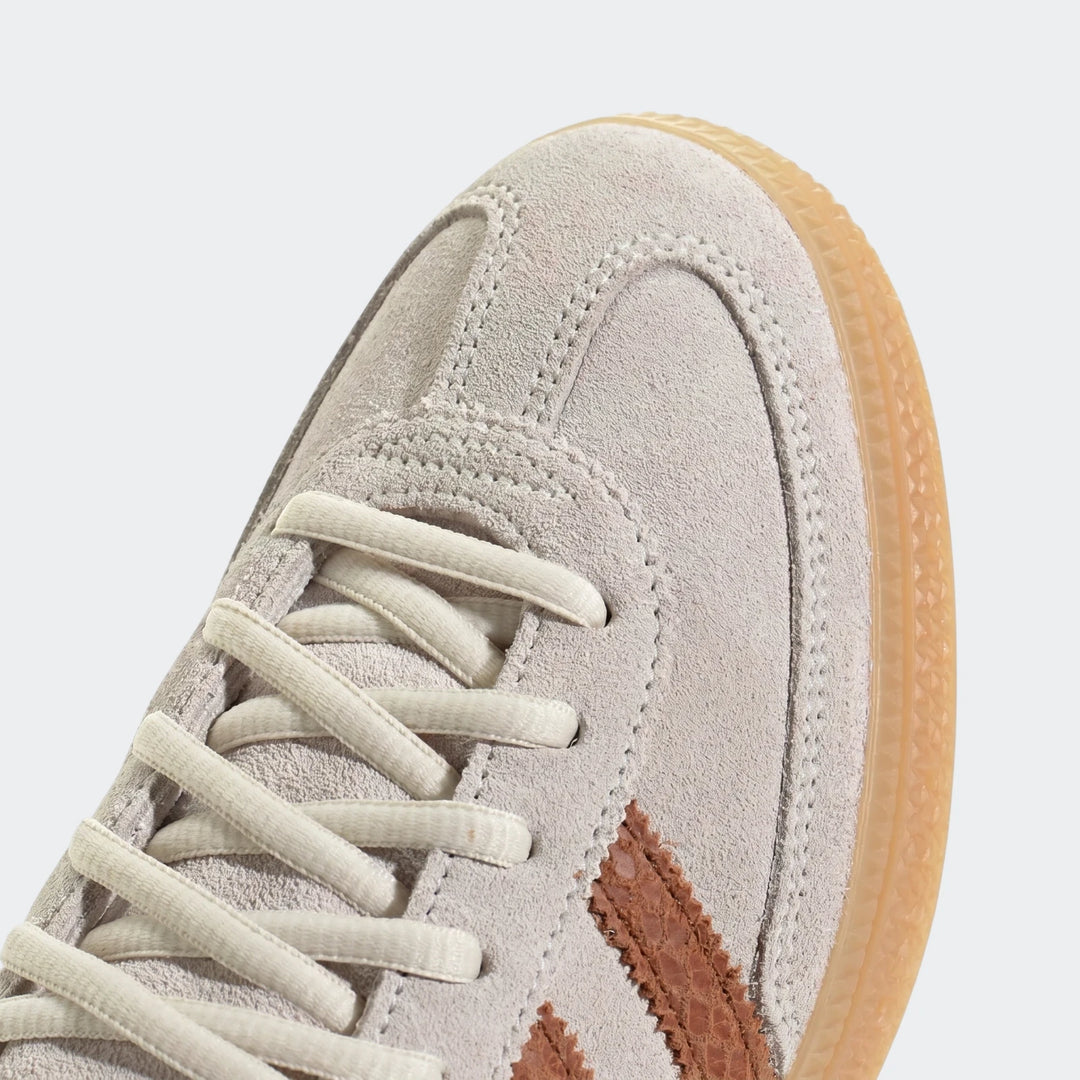 Close-up view of Adidas Handball Spezial shoes in light grey suede with brown signature stripes and white laces.