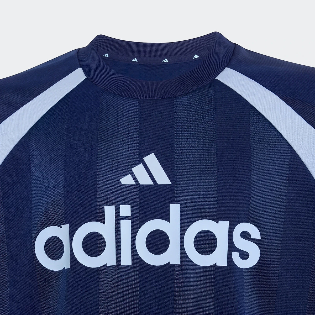 Close-up of a navy Adidas House Of Tiro unisex t-shirt featuring the white Adidas logo on the chest and light blue raglan