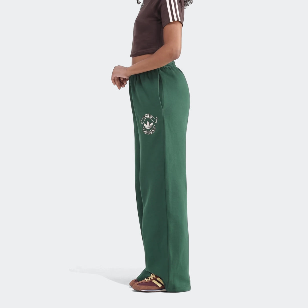 Dark green Adidas Infill Heritage Pants, a loose-fit style, worn by a model in a profile view against a plain background.