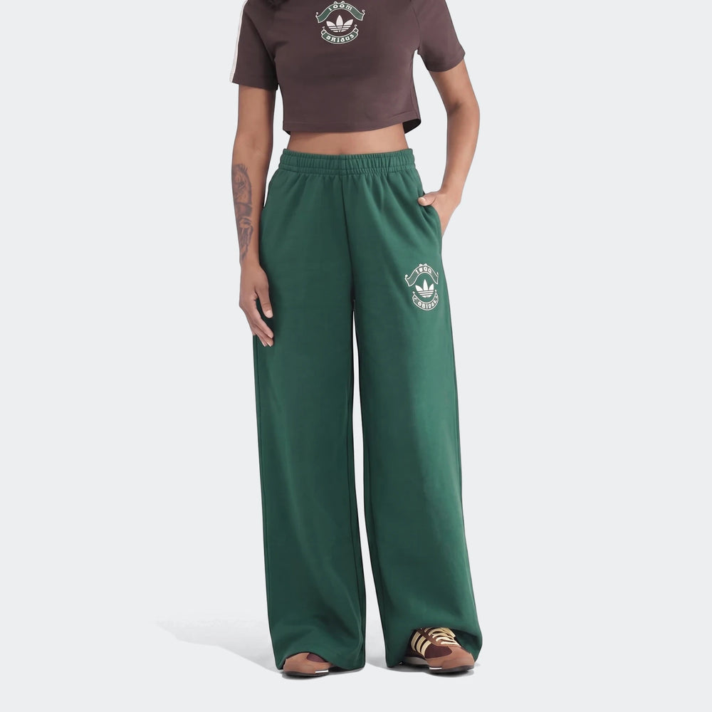 Green Adidas Infill Heritage wide-leg pants on a model, paired with a brown crop top, front view.