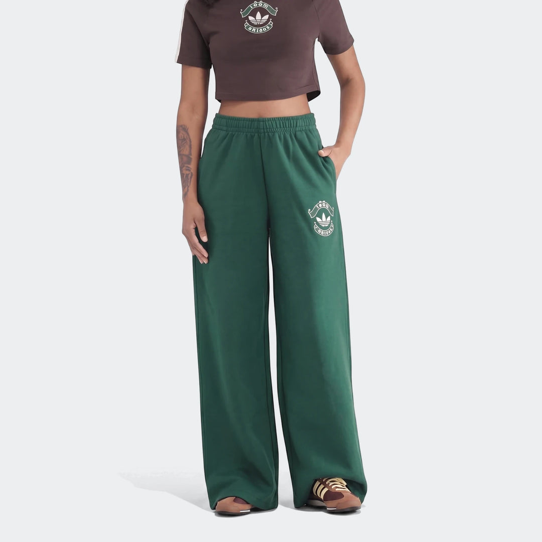 Green Adidas Infill Heritage wide-leg pants on a model, paired with a brown crop top, front view.