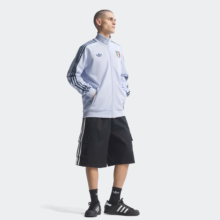 Full body shot of a male model wearing a light blue Adidas Italy Originals Track Top, black cargo shorts, and black Adidas